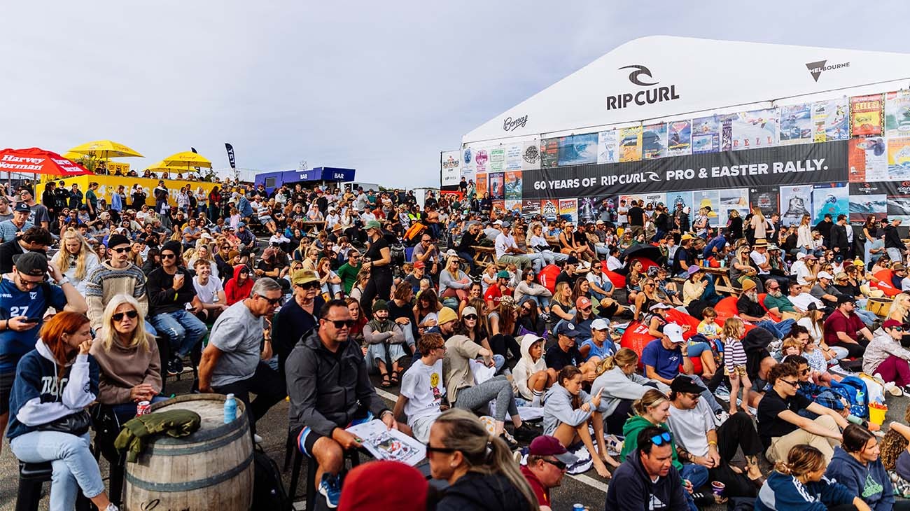 Large crowd at a Rip Curl event with branded tents and surfboards.