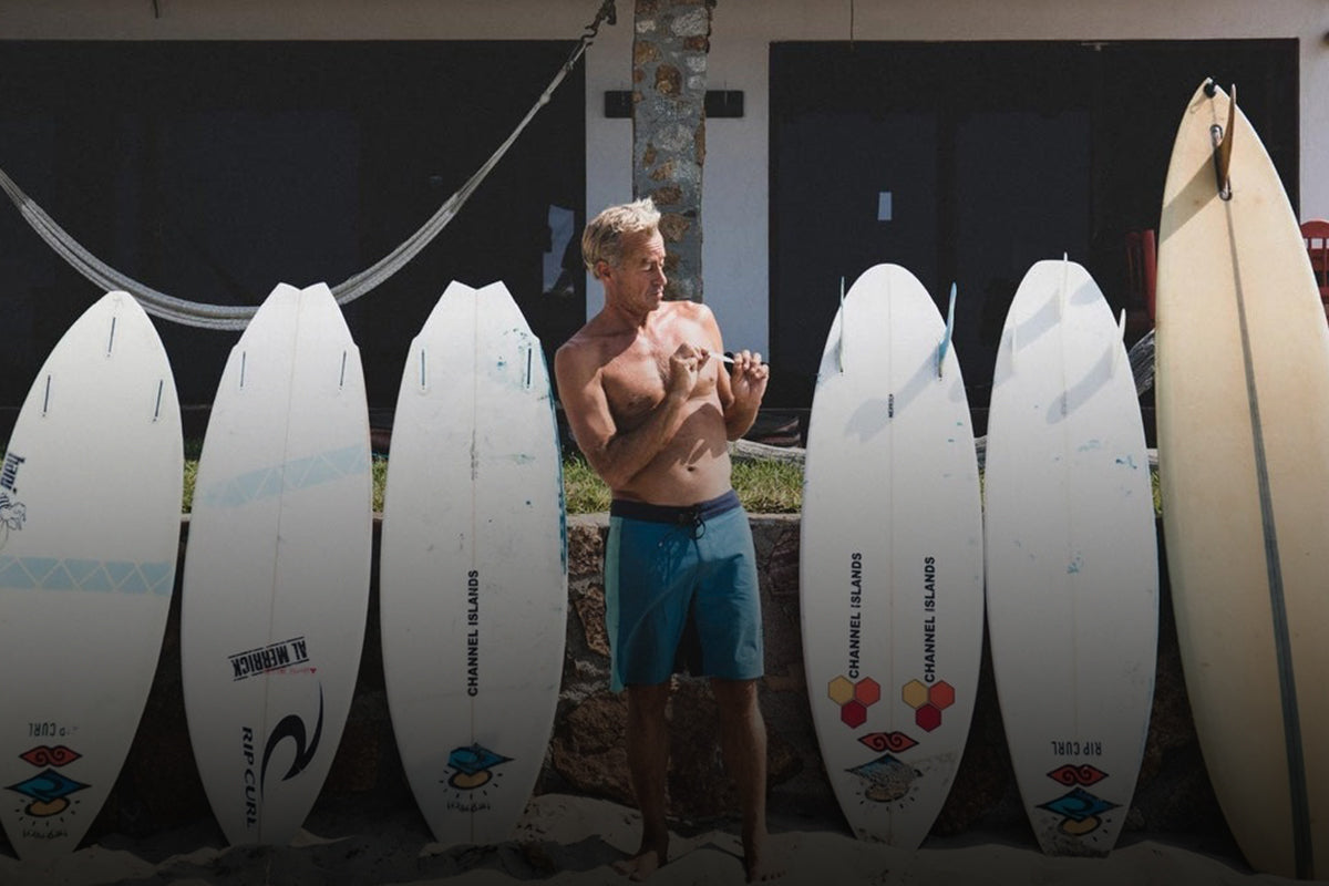 Tom Curren standing with surfboards