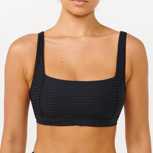 Black ribbed sports bra worn by a person on a white background