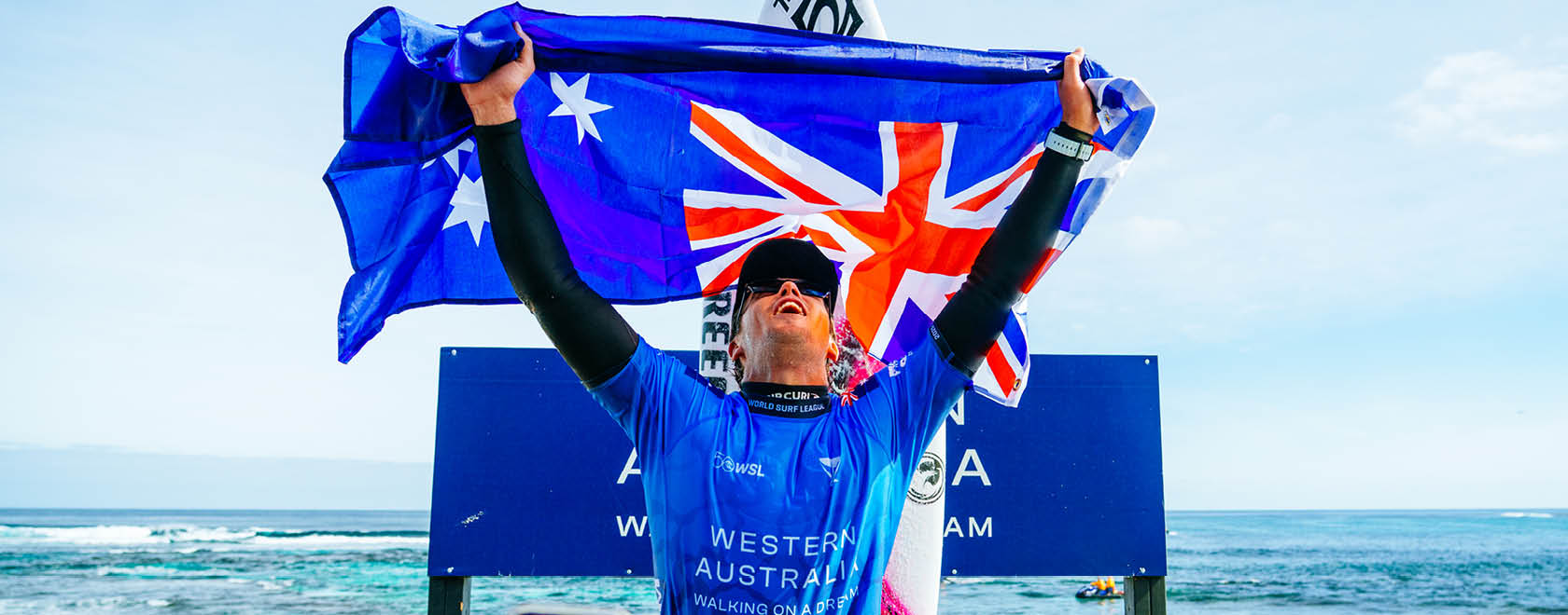 Person holding an Australian flag with a blue banner in the background