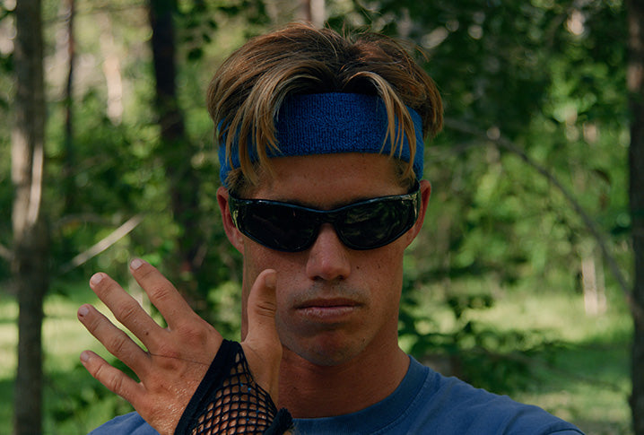 Person wearing sunglasses and a blue headband with a forest background