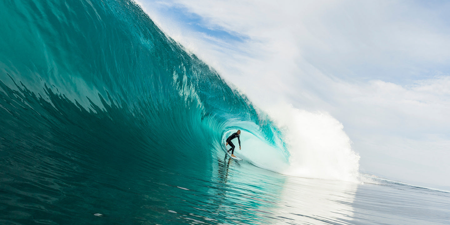 Surfer riding a large wave with a clear sky
