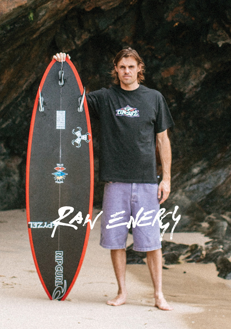 Man holding a surfboard with a rocky background