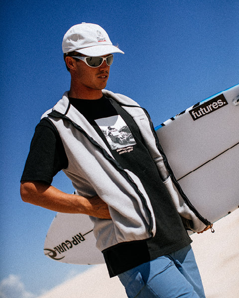 Person holding a surfboard with a clear blue sky background