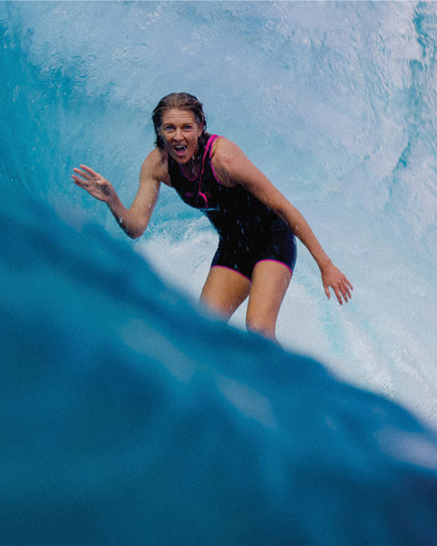 Person surfing on a wave with a close-up view of the water.
