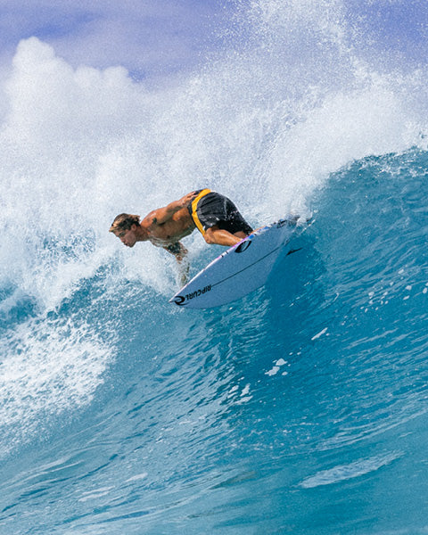 Surfer riding a wave on a surfboard with a blue sky background