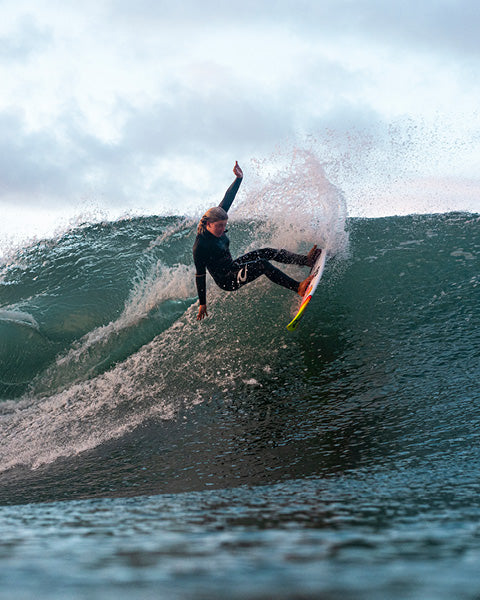 Person surfing on a wave with a cloudy sky