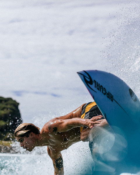 Person surfing with a blue surfboard in the foreground
